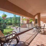 Spacious outdoor terrace with elegant metal furniture and lush garden view.